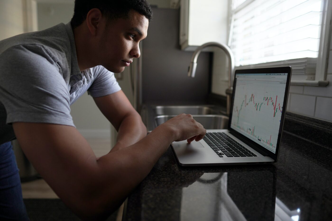 student investing.jpg Student looking at a stock trading chart on his laptop