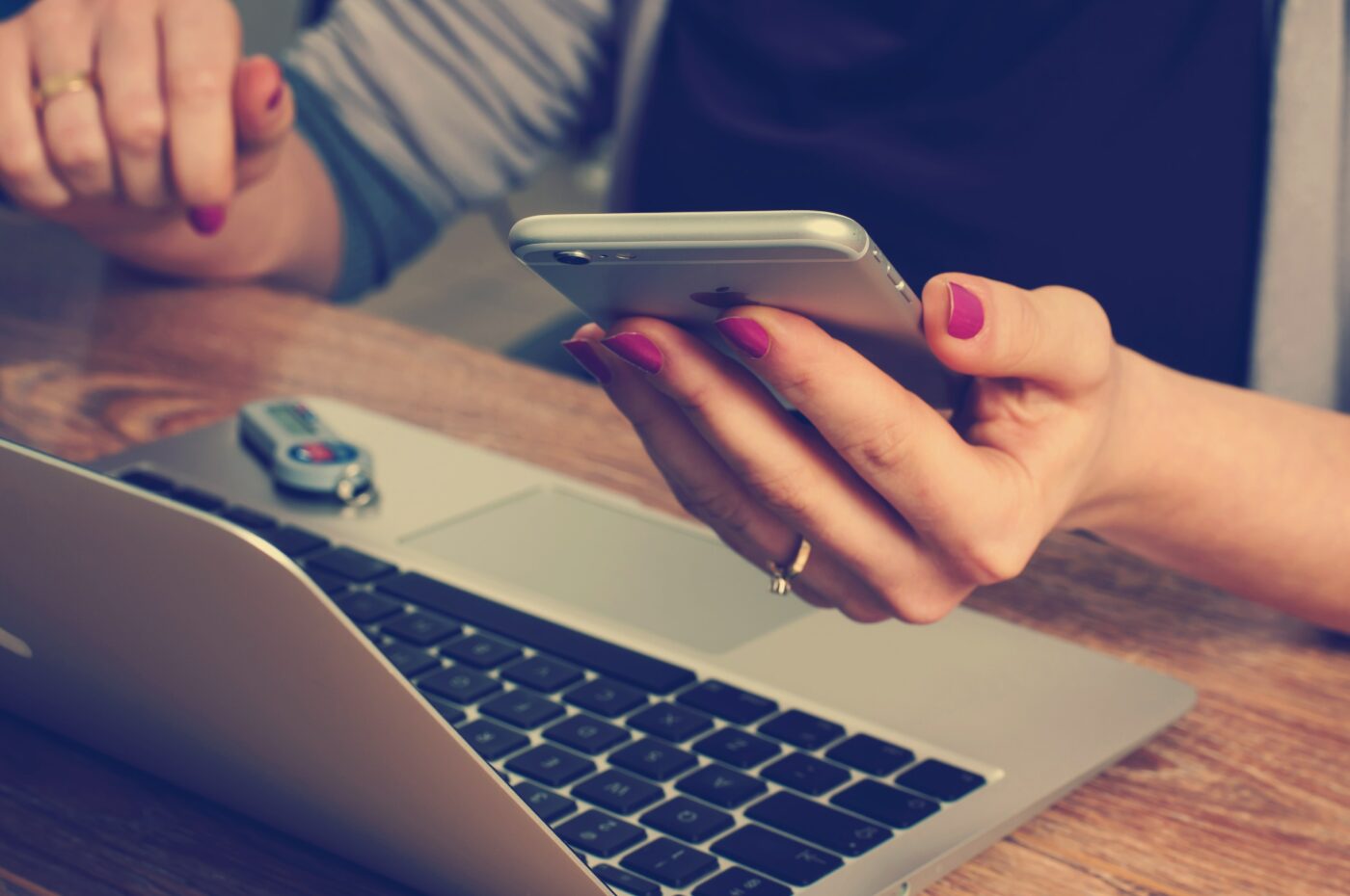student-finance-payment-dates-image-2.jpg A picture of someone sitting at their laptop with their phone in their hands - student finance payment dates