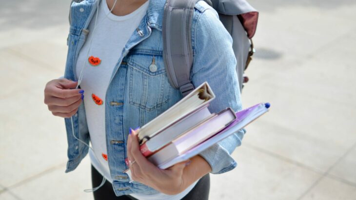 student-finance-payment-dates-image-3.jpg Woman walking with a backpack and books in her arms - student finance payment dates