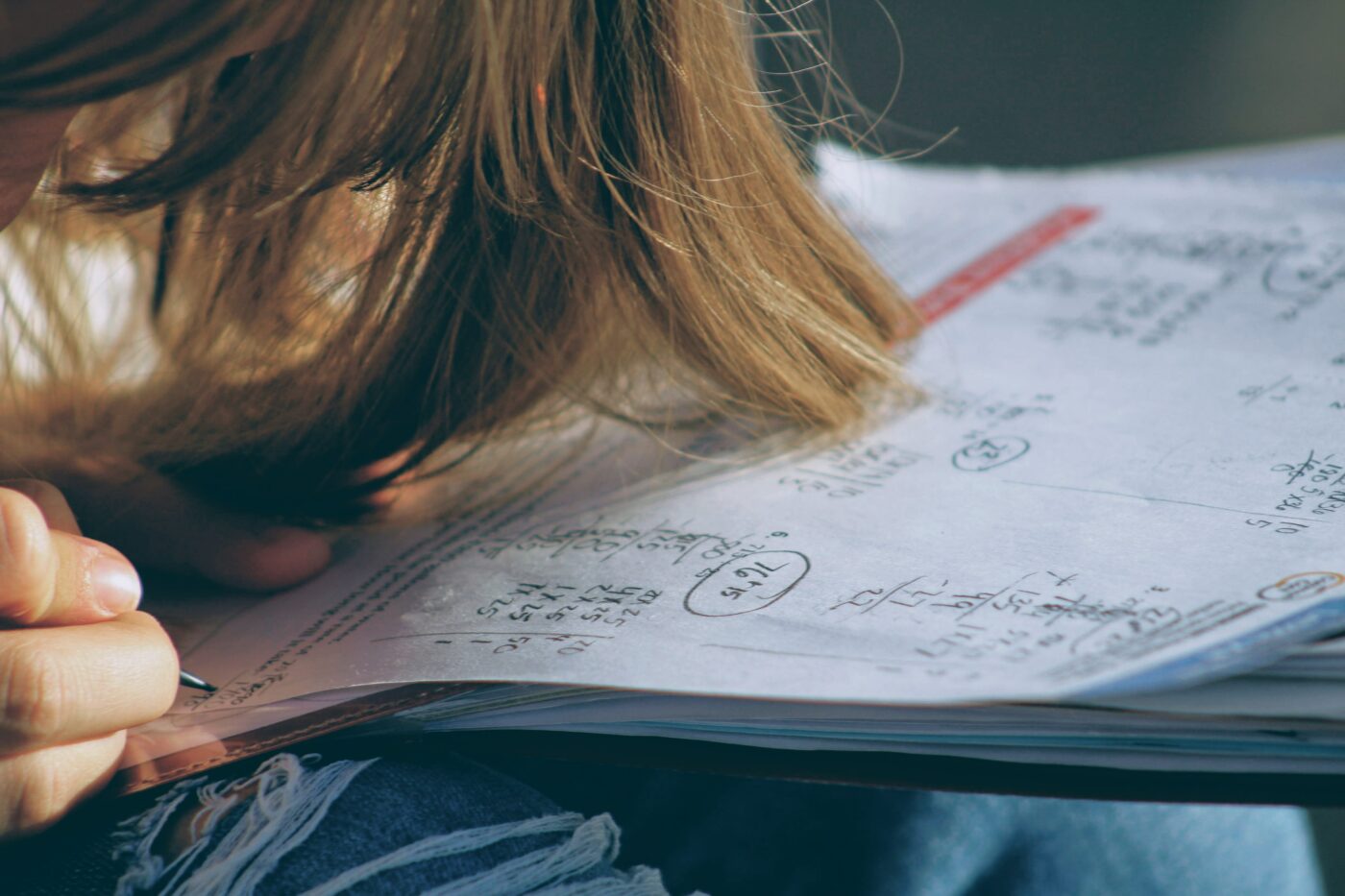 joshua-hoehne-AZrBFoXP_3I-unsplash.jpg Person with long hair hanging over their book writing study notes in a book
